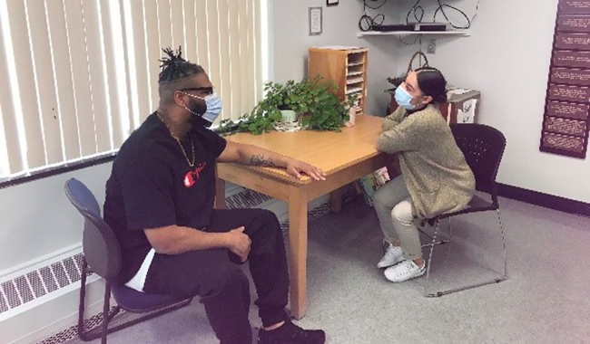 Two people sit talking at a table