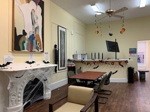 A lobby decorated with fake cobwebs, paper bats, and a happy Halloween sign strung across the counter