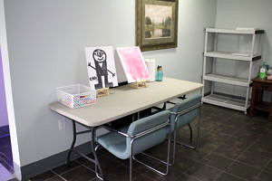A table with two chairs, art supplies and two paintings on easels