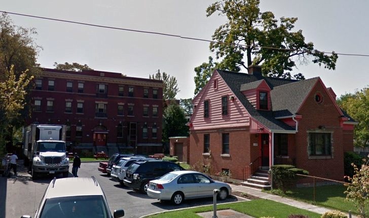 A smallish house in the foreground in front of a large brick building