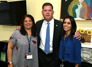 Mayor Marty Walsh standing with his arms over the shoulders of two CRJ staff members