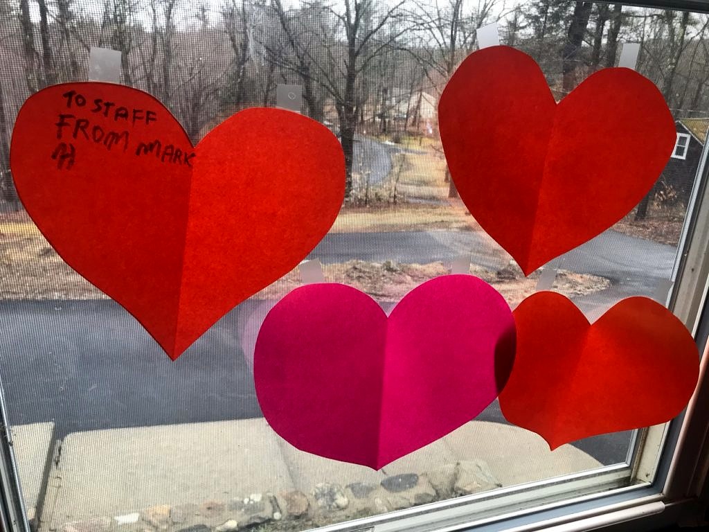 Red and pink paper heart cutouts taped to a window