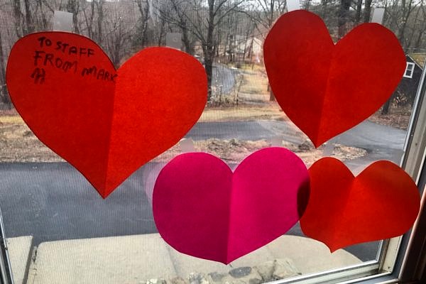 Red and pink paper heart cutouts taped to a window