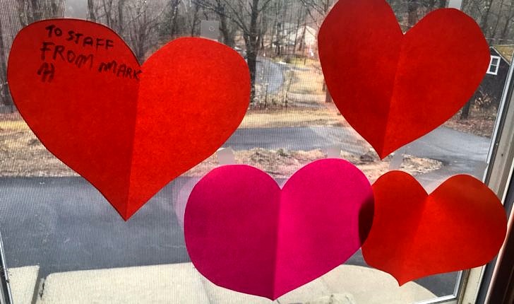 Red and pink paper heart cutouts taped to a window