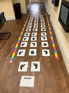A hopscotch court made of printed out pieces of paper showing hands and feet