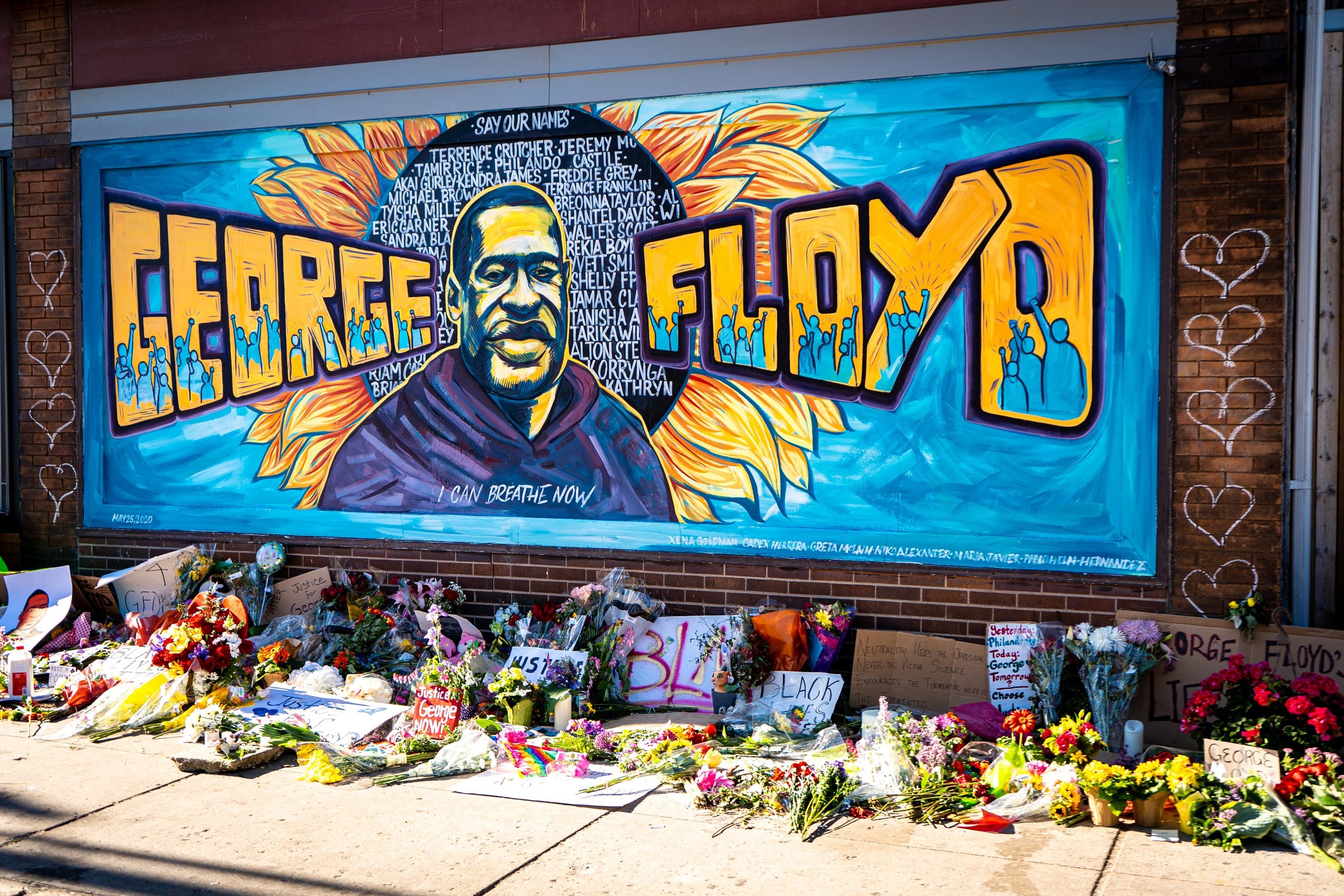 A memorial to George Floyd in Minneapolis featuring an image of his face and name on a brick wall