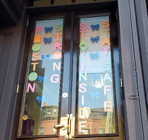 Colored letters arranged on the front door of McGrath House to say "Boston Strong. Stay Inside. Stay Safe."