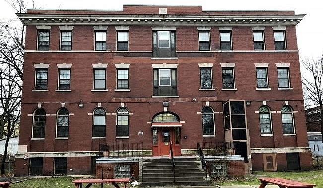 A three-story red brick building with picnic tables in front