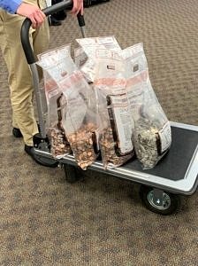 Large plastic bags filled with assorted coins on a rolling cart