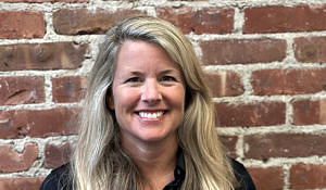 Portrait photo of Wendy Smith standing in front of a brick wall