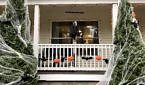 Halloween decorations on a front porch, including a skeleton with a veil, paper bats and pumpkins, and fake cobwebs