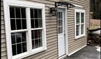 An exterior picture shows a new door with large windows on either side