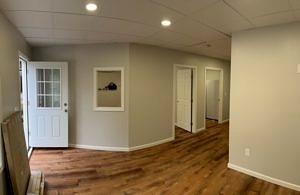 An interior photo of the completed work, showing a wood floor, brightly lit hallway, and doors to several rooms off the hallway